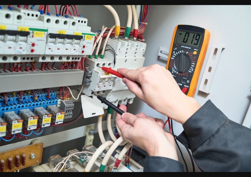 Imagem de um eletricista trabalhando em painel de disjuntores.
